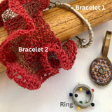 Two bracelets and a ring on a wooden stick with decorative elements.
